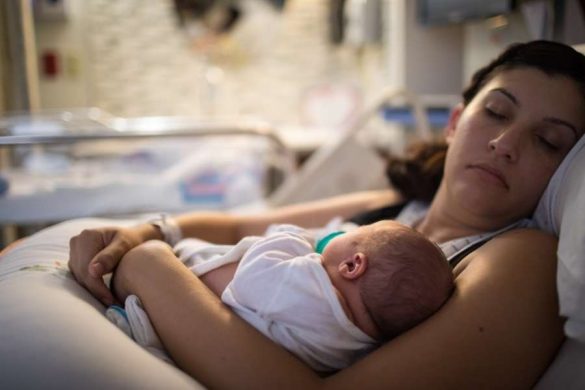 Jeune maman allongée avec son nouveau-né après l'arrivée de bébé en maternité