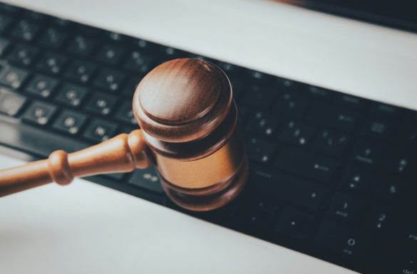 Un marteau de juge en bois posé sur un clavier d'ordinateur noir, illustrant les enjeux de l'éthique et législation IA dans le monde numérique.