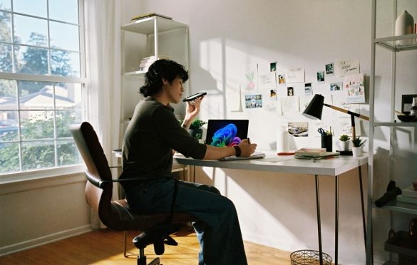 Un chercheur assis à son bureau utilise son smartphone et son ordinateur pour explorer les meilleurs outils IA pour la recherche scientifique et académique.
