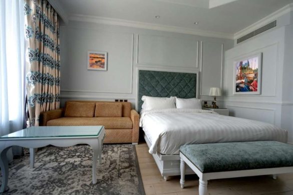 Une chambre d'hôtel confortable aménagée avec des meubles multifonctions, tels qu'un canapé convertible et un banc rembourré.