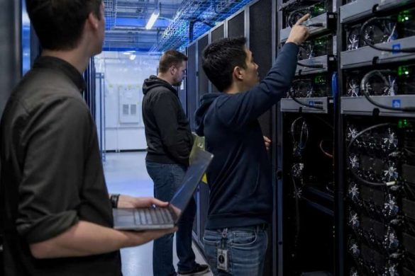 Des techniciens inspectent des serveurs informatiques abritant des cartes graphiques puissantes dans un data center.
