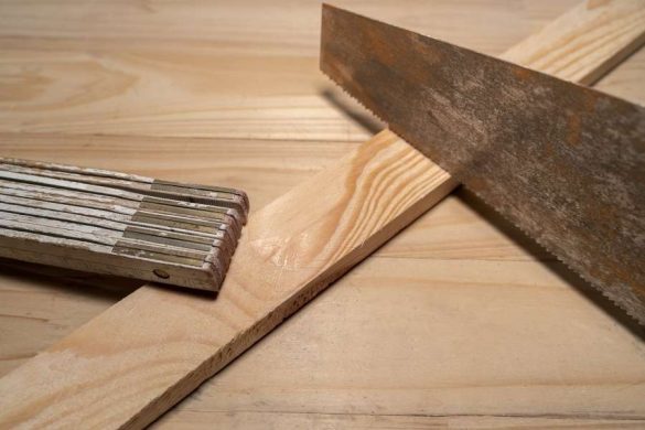 Une scie et une règle de mesure disposées sur le plateau en bois d'un établi pliant.