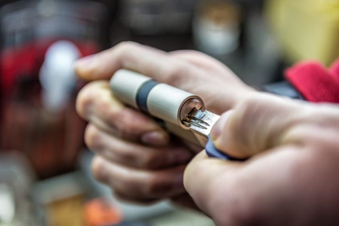 Un cylindre de serrure tenu en main lors d'une installation, utile pour réfléchir à l'importance de choisir le meilleur protège-cylindre.
